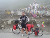Ladakh Author Cycle Expedition 2012 - rowerem po Indiach czas zacząć :) Po wielomiesięcznych przygotowaniach nareszcie nadeszła długo oczekiwana pora wyjazdu w Himalaje. Główne cele wyprawy to droga z Manali do Leh oraz najwyższe przełęcze Indii i Himalajów powyżej 5000m.npm. Dwa dni wcześniej wyjechałem pociągiem z Jeleniej Góry do Warszawy skąd startuje mój samolot do Delhi. Musiałem jeszcze tylko odebrać indyjską wizę i dokupić dużą ruską torbę do której wrzucę przyczepkę, sakwy i kilka innych rzeczy. Przelot zarezerwowałem już w grudniu rosyjskimi liniami lotniczymi Aeroflot. Na pokład mogłem zabrać aż 56kg bagażu w tym ponadgabarytowe pudło z rowerem. Ogólnie dwie sztuki bagażu do 23kg i do 10kg bagażu podręcznego. Wystarczy, nawet jak na miesięczną wyprawę rowerową po Indiach ;)  Dzień 1. 27.06.2012 Wylot. 0km Dwie godziny przed wylotem pojawiłem się na lotnisku Okęcie. Szybko znalazłem wózek aby nie dźwigać 46 kilogramowego bagażu i udałem się na odprawę. Nikomu nie przeszkadzało, że pudło za duże, że waży o 1kg za dużo. Nie musiałem nic dopłacać co mnie bardzo ucieszyło. Odprawę przeszedłem szybko i bezproblemowo. Rower musiałem zostawić po odprawie w pomieszczeniu dla niestandardowych bagaży. Przelot do Moskwy gdzie miałem przesiadkę trwał niecałe dwie godziny. Każdy z pasażerów dostał posiłek a także zimny i ciepły napój. Lot przyjemny i bez turbulencji. Po wylądowaniu w Moskwie ponowna kontrola i ponad 4h w międzynarodowym terminalu F w oczekiwaniu na lot do Delhi. Na moskiewskim lotnisku w przeciwieństwie do Okęcia można urozmaicić sobie czas surfując w sieci dzięki Wi-Fi. Tuż przed wylotem czułem się już jakbym był w Indiach. Wokół pełno opalonych hindusów i kilku mnichów. Samolot w Moskwy większy niż ten z Warszawy. Standard też wyższy. Na uwagę zasługuje multimedialny ekran dla każdego z pasażerów na którym można obejrzeć film, posłuchać muzyki czy pograć z gry. Mnie ucieszył port USB przez który mogłem podładować smartfon HTC One X i tablet Flyer. Na lotnisku Wi-Fi zżarło trochę prądu :) Schemat i procedura lodu ta sama co z Warszawy. Dzień zleciał bardzo szybko a raczej uciekł. Lecąc na wschód z prędkością ponad 900km/h pokonałem kilka stref czasowych i "straciłem" 5:30 godziny. W Delhi po wylądowaniu zamiast 23:00 była już 4:30 nad ranem czyli ze spania nici przynajmniej do kolejnej nocy już według tutejszego czasu. Czas lotu to ponad 5h, max wysokość ponad 11200m, prędkość około 907km/h a temperatura na zewnątrz -72.4st.C wg informacji na ekranach. Pod koniec lotu każdy pasażer musiał wypełnić formularz dla biura imigracyjnego który oddaje się na lotnisku podczas ostatniej kontroli.  Dzień 2. 28.06.2012 Ucieczka z Delhi. 88.34km, 17.1śr, 27.3max, 170m w górę, 4h28m30s, 46st.C Po wylądowaniu i odebraniu bagażu musiałem wszystko wypakować i od nowa poskładać. Skręcić rower i przyczepkę oraz porozkładać wszystkie rzeczy po sakwach. Pudło niestety nie wytrzymało trudów przelotu. Odebrałem je prawie w całości otwarte, na szczęście nic nie zginęło że środka. Pudło, torbę i kilka innych rzeczy planowałem oddać do czasu powrotu do przechowalni bagażu na lotnisku. Jednak cena 270zł za przechowanie bezwartościowej rzeczy skutecznie wybiła mi pomysł z głowy. Jak przewieźć rower z powrotem będę sie martwił przed wylotem z Indii. Tymczasem torbę ze zbędnymi rzeczami muszę wozić ze sobą, razem to jakieś 2kg więcej. Z bankomatu wybrałem kilka tysięcy rupii po czym opuściłem teren lotniska. Na zewnątrz przed 6:00 już 31st.C i dosyć duszno. Od razu zwracam na siebie uwagę "dziwnym" trójkołowcem i sakwami. Hindusi reagują na mój widok bardzo pozytywnie. Jedni się śmieją inni zaczepiają a jak tylko się zatrzymam to od razu wokół roweru zbiera się kilka osób. Pierwsze kilometry przemierzam dość szybko że średnią 20km/h. Po kilku godzinach udaje mi się wyjechać z Delhi. Liczyłem na mniejszy ruch za miastem niestety krajowa 1 w stronę Chandigarth jest bardzo ruchliwa mimo że płatna w dalszej części (nie dla rowerów). Niestety to najkrótsza droga w Himalaje więc nie mam wyboru. Droga jest bardzo szeroka, ma dwa a czasami i trzy pasy. Droga autostradą nie jest i korzystają z niej wszyscy od rowerzystów po dorożki. Wzdłuż drogi koncert życzeń, od nowo postawionych marketów po śmierdzące slumsy. Ogólne pełno śmieci i brudu a nawet zdechłych zwierząt. Od południa jechało mi się coraz gorzej nie tylko z powodu upału ale i przez zmianę czasu oraz brak snu. Co chwilę robiłem postój w zacienionym miejscu lub wchodziłem do przydrożnych knajpek na zimny napój z lodówki. Cena za butelkę wody to 10-20R/L. Cola, Fanta, Limca i inne za około 30R za 500-600ml. Na jednym z postojów zaczepił mnie hindus i zaproponował podwiezienie w okolice Chandigarth. W sumie nie zastanawiałem sie zbyt długo no i nie mogłem przepuścić okazji przejechania się kolorową ciężarówką Tata. Takich aut tutaj pełno, nie są zbyt szybkie ale na pewno wytrzymałe. W środku rozłożona kanapa więc mogłem się przespać. Geresz, bo tak mniej więcej miał na imię kierowca nie znał wielu słów po angielsku i nie mogliśmy za dużo porozmawiać. Ponieważ auto nie było zbyt szybkie, 50-60km/h szybciej jechać się nie dało Geresz kilka razy zatrzymał się aby napić się wody czy zjeść posiłek w zaprzyjaźnionym barze. Na wszystkim skorzystałem też i ja. Łatwiej jest w obcym kraju jak się ma tutejszego przewodnika. Chappati, jakieś ciepłe danie np. Aluu Palak, sos lub sałatka i herbata po angielsku (nasza bawarka) to typowy posiłek tutaj. W okolice Chandigarth dojechaliśmy kiedy było już ciemno. Geresz zaproponował abym spał w aucie a on sam będzie spał na aucie. Nie wypadało odmawiać.Nie musiałem szukać miejsca na nocleg tylko od razu iść spać.  Dzień 3. 29.06.2012 Ciężka droga do Shimla 54.44km, 11.4śr, 41.0max, 1526m w górę, 4h53m45s, 41st.C Wieczorem po kilku drzemkach podczas jazdy ciężko było zasnąć. W samochodzie było potwornie gorąco a przejeżdżające samochody i klaksony również nie pomagały. W nocy budziłem się wiele razy i rano dalej nie czułem się wyspany. Według polskiego czasu północ to tutaj 5:30. Nie tak łatwo zaczynać jazdę rowerem kiedy powinno się właśnie spać. Organizm potrzebuje kilku dni aby się przestawić. Chwilę po 7:00 pożegnałem Geresza i ruszyłem w kierunku miasta Shimla. Według znaków to około 90km. Droga jaką jechałem nazywała się Himalaya Express i była płatna ale nie dla mnie :) Od początku nie jechało mi się dobrze. W dodatku cały czas było już pod górę. Po kilku kilometrach zrobiłem przerwę i ponownie zasnąłem. Śmieszne, ponieważ dopiero co się obudziłem. Dziś już nie było aż tak upalnie jak wczoraj ale licznik i tak wskazywał ponad 40st. Praktycznie więcej odpoczywałem niż jechałem. Nogi odmawiały posłuszeństwa a głowa wcale nie miała ochoty do jazdy. Na postój wykorzystywałem każdy pretekst. Zatrzymałem się przy każdym źródełku oraz po to aby zrobić zdjęcia małpom siedzącym niedaleko drogi. Kiedy doczłapałem sie do miasta Solan 40km od Shimli postanowiłem że znajdę hotel i odpocznę resztę dnia. W końcu i tak mam nadrobione 200km a skoro organizm domaga się odpoczynku to lepiej tak zrobić niż np. się rozchorować. Solan to hinduska stolica grzybów jak informują znaki. Ze znalezieniem hotelu nie było problemów. Kawałek za centrum wszedłem do jednego. Cena za nocleg 500R (30zl). Obok restauracja więc mogłem liczyć też na posiłek. Zimny prysznic, zimna woda do picia oraz wiatrak na suficie postawiły mnie na nogi. Od 16:00 do wieczora wypiłem jeszcze kilka litrów wody z izotonikiem Penco. Na obiadokolację Palak Paneer - szpinak w sosie z serem , Chappati i sałatka. Spać kładę się wcześnie, po 20:00. Mam nadzieję, że jutro już będę czuł się lepiej i przyzwyczaję się do panujących tu warunków.  Dzień 4. 30.04.2012 Shimla 104.69km, 13.7 śr, 52.3max, 1638m w górę, 7:37:32, 39st.C Wyspany i wypoczęty wyruszyłem z hotelu po 7:00. Pierwsze kilometry z Solan w kierunku Shimli lekko z górki, potem już tylko pod górę, przeważnie kilka procent ale krótkie odcinki powyżej 10% też się zdarzają. Czuję, że nie mam jeszcze pełnej mocy w nogach ale dziś i tak już jest lepiej. Przynajmniej wykonałem dziś dzienny limit 100km. Podczas odpoczynków kilka razy zostałem "napadnięty". Hindusi proszą o zdjęcie z rowerem i że mną. W pewien sposób próbuję to wykorzystywać. Każdego znającego angielski podpytuję o ważne dla mnie informacje. Do mojej kolekcji zwierzyńca dorzuciłem dziś zdjęcie pary jaków. Spróbowałem także nowej potrawy zakupionej za 10R przydrożnej budy od starca. Masala z pieczoną bułką. Groch, cebula, pomidor, papryka, ziemniaki kilka innych warzywa i cała kasza przypraw. Podane na zimno. Zero jakichkolwiek zasad czystości podczas przyrządzania i podania ale smakowało nieźle. Za łyżkę posłużył mi kawałek gazety :) Do Shimli dojechałem koło południa. Spore miasto i duży ruch jak na ponad 2000m.npm. Droga nie zaprowadziła mnie w miejsce które planowałem zobaczyć więc musiałem wejść kilkaset metrów w górę z rowerem. Shimla do była stolica brytyjskiej kolonii w Indiach. Przypominają o tym stary chrześcijański kościół oraz budynki przy głównej ulicy turystycznej. W Shimli zjadłem lody z maszyny (dwa za 50R), korzystając z okazji wybrałem trochę gotówki z bankomatu, popstrykałem kilka zdjęć i ruszyłem dalej. Oczywiście nie odbyło się bez zaczepek z prośbą o zdjęcie z rowerem. Od Shimli dalej ciągle w górę drogą 22 kierowałem się w stronę następnego celu czyli Jalori Pass. Przełęcz będę próbował atakować jutro. Mam do niej około 94km. Z braku miejsca do na rozbicie namiotu oraz jakiegokolwiek hotelu o możliwość przespania zapytałem w przydrożnej restauracji. Za 200R mogłem skorzystać z jeszcze nie dokończonego pokoju dla gości oraz z wody. Niezbyt wygórowana cena a i tak już nie miałem siły kręcić dalej a do zmroku pozostało niewiele czasu. Spanko w śpiworku na podłodze. O 20:30 przyjemna temperatura 21st.C na wysokości ponad 2500m.npm 3km przed miastem Narkanda :)  Dzień 5. 1.07.2012 Męczarnie pod Jalori Pass 93.77km, 12.9śr, 46.4max, 1740m w górę, 7:15:14, 43st.C Do zmiany czasu chyba już się przyzwyczaiłem, przynajmniej już nie mogę narzekać na brak snu czy niewyspanie. Chwilę po 7:00 wyruszyłem w dalszą drogę. Miasto Narkanda jako duża plamka na mapie okazała się przełęczą z kilkoma budynkami na wysokości około 2733m.npm. Zrobiłem tu moje jedyne zakupy dziś. Za 10R kupiłem dwa pomidorki i ogórka na kanapki. Wczoraj kupiłem chleb tostowy, w połączeniu z pasztecikiem od Sante wyszły całkiem niezłe kanapki. Ostre i mocno przyprawione hinduskie potrawy są dobre ale nie da się ich jeść ciągle. Od Narkandy było solidnie z góry, ponad 28km i 2000m w pionie w dół. Niestety im niżej tym bardziej gorąco. W dolinie wielkiej szarej rzeki Sutlej na około 730m było już powyżej 40st.C. To wystarczyło żebym znów się zagotował i opadł z sił. Z doliny na przełęcz pozostało jeszcze 45km i 2500m w górę. Co kilka kilometrów a czasami i kilkaset metrów zatrzymywałem się na odpoczynek w cieniu. Korzystałem też z każdej okazji na uzupełnienie wody i ochłodzenie się. Chwilami wydawało mi się, że więcej odpoczywam niż jadę. Chwilami nachylenie przekraczało 15% a ja byłem zmuszony prowadzić rower co nie zdarza mi się zbyt często. Przed 19:00 dotarłem do Lajheri, ostatniego miasteczka przed przełęczą. Tutaj uzupełniłem wodę i zacząłem rozglądać się za noclegiem. Po raz kolejny uśmiechnęło się do mnie szczęście. Przechodzący starzec stwierdził, że wyglądam na zmęczonego. Ja zapytałem o miejsce do spania. Zaproponował miejsce na rozbicie namiotu na swoim ganku przed domem. Rozbijanie namiotu okazało się sporą atrakcją dla mieszkańców niewielkiej chatki. Poczęstowano mnie herbatą oraz śliwkami. Tutejsze mirabelki są o wiele słodsze i soczyste od naszych. W zamian odwdzięczyłem się lizakami dla dzieci. Nocleg na wysokości 2450m.  Dzień 6. 2.07.2012 Jalori Pass 103.83km, 13.5śr, 49.6max, 1244m w górę, 7:51:37, 39st.C Hindusi wstają wcześnie. Już o 5:00 chyba cała rodzina była na nogach. Ja wstałem dopiero przed 7:00. Na drogę dostałem jeszcze Allu Prota czyli coś jak nasz placek ziemniaczany z cebulą. W nocy błyskało się a kiedy wyruszałem kropił deszczyk. Zaraz za Lajheri skończył się asfalt i do przełęczy był tylko piach z kamieniami po których ciężko się jechało. Chwilami znów musiałem prowadzić rower ze względu na spore nachylenie. Po prawie sekcję godzinach dotarłem do Jaroli Pass na 3120m. Na przełęczy jak zresztą wszędzie tutaj kilka sklepików z napojami, chipsami i tabaką. Mnie jednak bardziej zainteresowała stojąca tu gompa na tle której zrobiłem zdjęcie. Zjazd w dół również okazał się wymagający przez kiepską nawierzchnie i nachylenie ponad 15%. Kilka kilometrów niżej i jakieś 1000m w dół było już lepiej. Chwilami jednak asfalt przeplatał się z kamienistymi odcinkami. W dolinie na wysokości 1100m znów upał. 39st.C. Tu jednak w kierunku Manali wjechałem w kilkukilometrowy tunel gdzie było znacznie chłodniej. Następne kilometry to lekko w górę wzdłuż rzeki po której pływają pontony Raftingowe. Na jednym z postojów moja maszyna znów wzbudziła ciekawość kilku hindusów. Swoje zainteresowanie kierują przede wszystkim na licznik, przyczepkę oraz ładowarkę słoneczną. W Kullu zrobiłem małe zakupy. Kupiłem między innymi tutejsze słodycze sprzedawane na sztuki których wybór jest przeogromny a także kilka rodzajów małych hinduskich cukierków. Nocleg znalazłem około 25km przed Manali w mieścinie Dobhe. Tuż przy drodze po prawej stronie po schodkach znajduje się mały domek w którym można tanio wynająć pokój. Ciekawie wyglądały negocjacje w kwestii ceny za nocleg. Starszy pan usiadł ze mną na krześle i zaczęliśmy rozmowę. Był zainteresowany skąd jestem i gdzie jadę. Powiedział, że już spało u niego kilku rowerzystów w tym również z Polski. Musiał chyba mieć dobre doświadczenia z Polakami bo wytargowałem satysfakcjonującą cenę 300R razem z kolacją :) Na kolację podano oprócz dobrze mi już znanej Chappati potrawkę z cukinii oraz sałatkę. Po kolacji starszy pan opowiadał jeszcze o ciekawych miejscach w okolicy Manali. Zachęcał między innymi abym odwiedził muzeum świątyń w Naggar prasa centrum Manali. Przed spaniem poprawiłem jeszcze hinduskimi słodyczami i chwilę po 22:00 udałem się na odpoczynek.  Dzień 7. 3.07.2012 Niespodzianki... 51.24km, 9.8śr, 37.6max, 1336m w górę, 5:11:30, 37st.C Wjazd na Przełęcz RohtangWjazd na Przełęcz RohtangPlanowałem zdobyć dziś Przełęcz Rohtang i nic z tego nie wyszło. Do Manali wszystko szło według planu. Zakupy, wypłata gotówki z bankomatu, kupienie leku na AMS w aptece, znalezienie Wi-Fi. Wszystko udało się bez problemu. Jednak kilka kilometrów za Manali wybuchła opona. Po takim wystrzale wiedziałem, że nie jest dobrze. Dziura na 2cm w tylnej oponie. Po raz kolejny żałuję, że w przyczepce nie mam takiego samego koła jak w rowerze. Załatał bym oponę, zamienił z tą z przyczepki i było by po kłopocie. Na kolejnej wyprawie już nie popełnię tego samego błędu. Na oponie która wystrzeliła przejechałem ponad 5000km bez flaka. A tu nagle taki pech. Musiałem wrócić się do Manali i mieć nadzieję na znalezienie sklepu rowerowego. W tym momencie mogłem już zapomnieć o zdobyciu Rohtang. Powrót do Manali na piechotę trwał prawie godzinę, kolejną godzinę szukałem sklepu rowerowego ponieważ nawet sami mieszkańcy nie byli pewni czy takowy się tu znajduje. Okazało się, że jest tu tylko serwis rowerowy ale części z nim niewiele o oponach nie wspomnę. Odesłano mnie do innego serwisu gdzie opony powinny być. No i były, tylko nie w takim rozmiarze jak potrzebuję. Mieli tylko 26 lub 28 cali. Mojej trekkingowej 7-setki niestety nie. Serwis-men na pękniętą oponę założył mega łatę a ja przerzuciłem oponę z tyłu na przód gdzie mam nową antyprzebiciową Rubenę. Teraz przez łatę przednie koło lekko podskakuje ale przynajmniej mogę jechać dalej pomimo straty połowy dnia. Przy najbliższej okazji postaram się coś kupić, może z Keylong a może dopiero w Leh. Teraz jednak muszę uważać na tą oponę co nie jest wcale łatwe przy wielu kamienistych odcinkach tutejszych dróg. Ponownie podjazd zacząłem po 15:00 zatrzymując się jeszcze w cukierni na małe co nie co. Kilka kilometrów za miastem zaczęły się moje ulubione serpentyny. Minąłem już również kilka posterunków wojskowych po drodze. Jednak żołnierze jako jedyni tutaj nie zwracają na mnie większej uwagi. Na nocleg wybrałem sobie polankę na wysokości 2600m niedaleko drogi na której jak widać po śladach pasło się coś niedawno. Tutejsi straszą grasującymi tu lisami i niedźwiedziami. Po chwili kawałek dalej zatrzymał się samochód z którego wyszła spora hinduska rodzina która postanowiła urządzić sobie tutaj grilla. Mieli że sobą duży namiot który chcieli rozłożyć dla dzieci. Nie wychodziło im to najlepiej i poprosili mnie o pomoc. I w ten sposób załapałem sie na hinduskiego grilla. Kurczak na ostro z sosem, drinki z whisky, muzyka i taniec z Punjab. Tak bawią sie hindusi po za domem. W domu z przyjaciółmi, znajomymi koszar nie jedzą, alkoholu nie piją. Ale w rodzinnym towarzystwie po za domem potrwają się świetnie bawić. Podczas rozmowy dowiedziałem się wiele o ich życiu i zwyczajach. Pytali też sporów o Polskę i polskie zwyczaje. Impreza zakończyła sie chwilę po zmroku. Oni zjechali do hotelu w Manali a ja zostałem na polance na noc. Nie ma tego złego co by na dobre nie wyszło. Gdyby nie awaria grilla by nie było. Zresztą może to i lepiej że czasami coś nie idzie tak jak to sobie zaplanuję. Tak przynajmniej mam więcej przygód a dni nie są tak podobne do siebie. Do Rohtang 38km a do Kunzum La mniej niż 100. Jednak aby zdobyć jutro Kunzum nie mogę się obijać jak dziś :) W sumie dzisiejszy dzień mogę zaliczyć jako odpoczynek. 50km i brak oznak zmęczenia.  Dzień 8. 4.07.2012 Rohtang Pass ZDOBYTE ale problemów ciąg dalszy. 66.46km, 9.7śr, 35.2max, 1504m w górę, 6:47:56, 10-21st.C Dopiero co zasnąłem to zaczął padać deszcz. Początkowo lekko, potem mocniej a po północy rozpętała sie ulewa. Namiot mam nowy ale odporność na deszcz o wiele słabsza niz w moim poprzednim. Przez kilka godzin największej ulewy musiałem bronić sie przed wodą. Ponownie zasnąłem po trzeciej kiedy deszcz nie był już tak intensywny. Gdy obudziłem się rano w namiocie miałem kilka małych kałuż a karimata i śpiwór były mokre. Kiepska perspektywa przed najwyższymi przełęczami które akurat teraz mam zdobywać. Mam też kolejny poślizg po wczorajszych przebojach z oponą. Przestało padać przed dziewiątą. Szybko się pozbierałem i ruszyłem w górę. Zaczęło się serpentynami i lekkim nachyleniem. W trakcie jazdy mogłem podziwiać ponad stu metrowe wodospady kiedy tylko chmury ich nie zasłaniały. Kiedy chmury odsłoniły więcej zobaczyłem sznur samochodów wspinających się kilkaset metrów wyżej. Niestety przez następne kilka godzin nie było zupełnie nic widać. Gęsta mgła ograniczała widoczność do 20-30 metrów. Większość kierowców jeździła na światłach awaryjnych, trąbili też dwa razy częściej niż zwykle. Chmury rozgoniły się dopiero na wysokości około 3000m. Moim oczom ukazały się ogromne panoramy, rozległe doliny i wysokie zaśnieżone szczyty. Wszystko wydawało się takie wielkie, o wiele większe niż w Alpach. Fantastyczne widoki. Większość samochodów jechała do osady Marhi w której hindusi zrobili ośrodek narciarski. Wyżej natrafiłem na długi korek. Po ostatnich opadach na górnym nie asfaltowym odcinku powstały kałuże błotne i samochody mają problem z przejechaniem. Generalnie większość drogi na przełęcz jest utwardzona ale jest jeszcze kilka odcinków gdzie są kamienie i jedzie się źle. Prawie cały korek udało mi się ominąć przy dopingu kierowców i turystów. Jedynie podczas mijania aut musiałem odstać z godzinę bo nie miałem jak się przecisnąć. Mimo wszystko przez korek straciłem kilka godzin. Wydaje mi się, że hindusi są sami sobie winni. Nie potrafią przepuszczać. Tego zatwardzenia można by uniknąć gdyby mieli większą kulturę jazdy. Hindus wciska klakson i nie patrzy że jest wąsko, że może nie przejechać. Korek był tak długi, że większość aut będzie pewnie stała do jutra. Kiedy już się wydostałem do przełęczy miałem spokój i ciszę, prawie zerowy ruch :) Po kilku kolejnych serpentynach a od Manali jest ich 54 nareszcie jest - Rohtang Pass i 3978m.npm! To mój rekord jeśli chodzi o wysokość podjazdu. Na pewno nie ostatni podczas tej wyprawy. Na przełęczy znów mgła i żadnych widoków. Dobrze, że chociaż tablica jest, pękniętą ale jest. Po raz 10 chyba dziś hindusi prosili o zdjęcie ze mną bądź rowerem. Ciekawy przerywnik dla jazdy. Pytają też jak mam na imię do chcą wrzucić zdjęcie na FB. Zjazd z Rohtang do Gramphu do tylko serpentyny :) Ale nie liczyłem ile :) Im niżej tym gorsza droga. Okolice samej przełęczy mają najlepszą nawierzchnię. Szeroką na 6 metrów i idealnie równą. W Gramphu na rozjeździe długo zastanawiałem się czy jechać na Kunzum Pass (4500m). Wiedziałem, że droga do tej przełęczy nie jest najlepsza a muszę uważać na oponę która jest rozerwana. Postawiłem zaryzykować i ruszyłem w kierunku miasta Kaza jak pokazują znaki. Na chwilę wyszło słońce więc wykorzystałem ten moment na podsuszenie rzeczy po nocnej ulewie. Na drodze nie dość, że jest pełno kamieni to jeszcze co chwilę w poprzek drogi płyną spore strumienie. Przez kilka udało mi się przejechać a przez jeden musiałem przejść ponieważ był dość głęboki a strumień wartki. Na kolejnym zmoczyłem buta jak bym miał mało mokrych rzeczy. Po około 7km kolejny strumień a raczej rzeka była barierą nie do przejścia. Zbyt wielka woda aby przejść z rowerem. Niestety byłem zmuszony się wrócić. Dwaj motocykliści również nie ryzykowali i zawrócili. Szkoda bo na przełęczy znajduje się piękna stupa no i to 4500m.npm. W drodze powrotnej na kamieniach pękł mi przedni bagażnik, nie wytrzymał jeden że spawów. Na razie podwiązałem linką i maksymalnie go odciążyłem. Zgubiłem też moją ulubioną chustę. Pewnie została gdzieś przy jakimś źródełku. Nocleg na wysokości 3500m na pastwisku z końmi.   